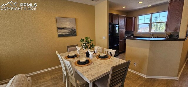 dining room featuring wood finished floors, baseboards, and recessed lighting