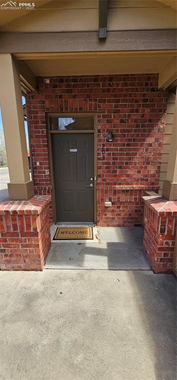 entrance to property featuring brick siding and a porch