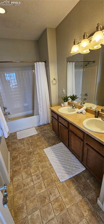 bathroom featuring a sink, shower / bath combo with shower curtain, double vanity, and a textured ceiling