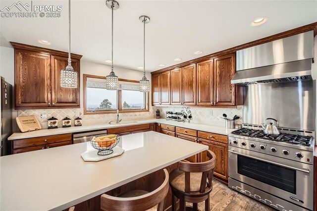 440 Scrub Oak Cir, Monument, CO 80132 - kitchen featuring stainless steel appliances, wall chimney exhaust hood, a sink, a breakfast bar, and tasteful backsplash