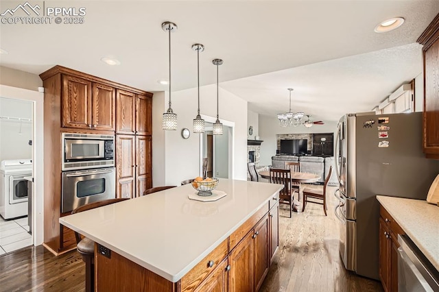 440 Scrub Oak Cir, Monument, CO 80132 - kitchen featuring stainless steel appliances, washer / dryer, dark wood-style flooring, light countertops, and a center island