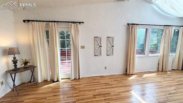5125 Thistle Ct, Colorado Springs, CO 80917 - doorway featuring light wood finished floors, vaulted ceiling, plenty of natural light, baseboards, and a textured ceiling