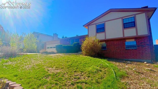 5125 Thistle Ct, Colorado Springs, CO 80917 - back of house featuring brick siding, a yard, and a chimney