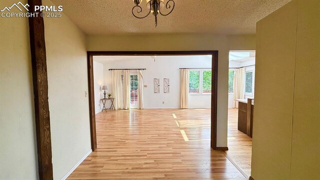 5125 Thistle Ct, Colorado Springs, CO 80917 - corridor featuring light wood-style floors, a textured ceiling, a chandelier, and baseboards