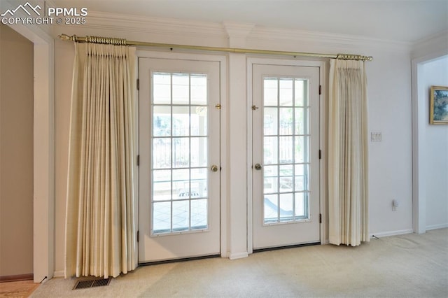 doorway with crown molding, carpet, baseboards, and visible vents