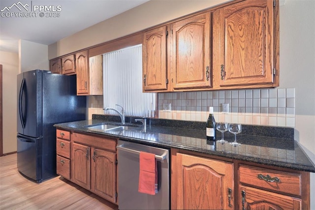 kitchen with a sink, light wood finished floors, freestanding refrigerator, tasteful backsplash, and stainless steel dishwasher