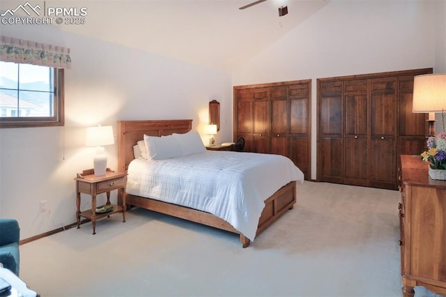 bedroom featuring two closets, light carpet, baseboards, ceiling fan, and high vaulted ceiling