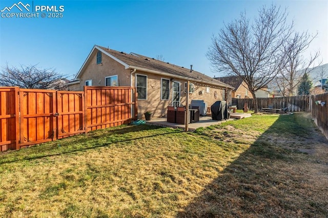 back of house with a gate, a lawn, a fenced backyard, a patio, and stucco siding