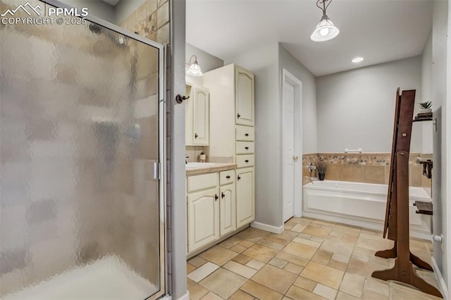 bathroom featuring a shower stall, vanity, stone finish flooring, baseboards, and a garden tub