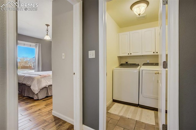 laundry room featuring separate washer and dryer, light wood-style flooring, baseboards, and cabinet space