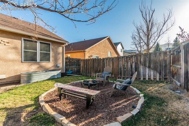 view of yard featuring a fenced backyard and a fire pit