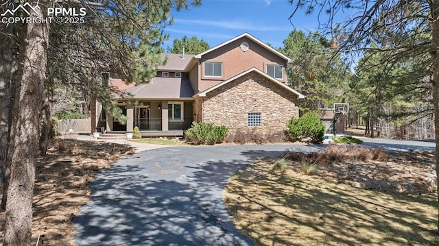 view of front of house with a porch, stucco siding, and stone siding