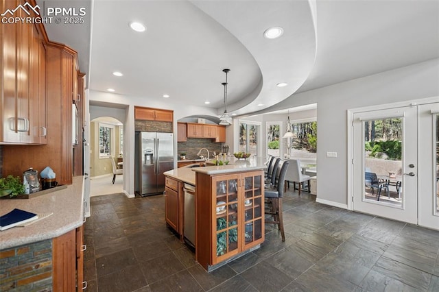 kitchen with baseboards, recessed lighting, appliances with stainless steel finishes, arched walkways, and a sink