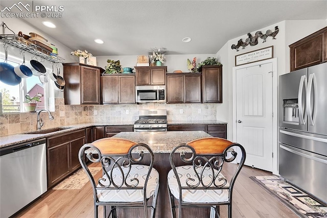 kitchen featuring light wood-style floors, dark brown cabinets, stainless steel appliances, and a sink