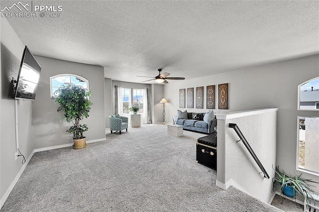 living room with ceiling fan, carpet floors, a textured ceiling, and baseboards
