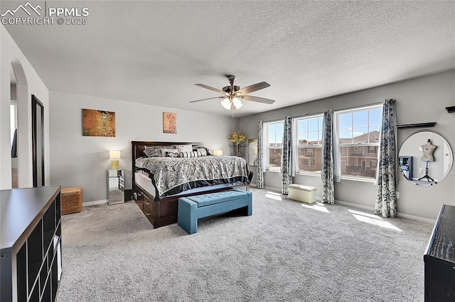 carpeted bedroom featuring arched walkways, baseboards, a ceiling fan, and a textured ceiling