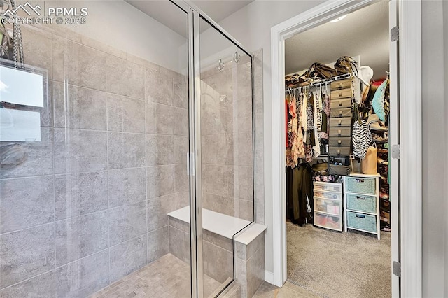 bathroom featuring a shower stall and a walk in closet