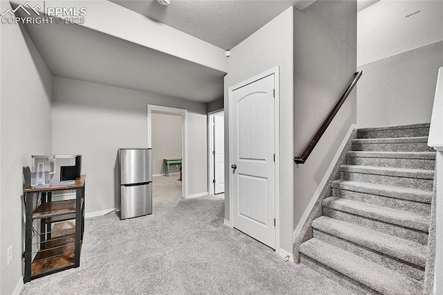 staircase with baseboards, carpet flooring, and a textured ceiling