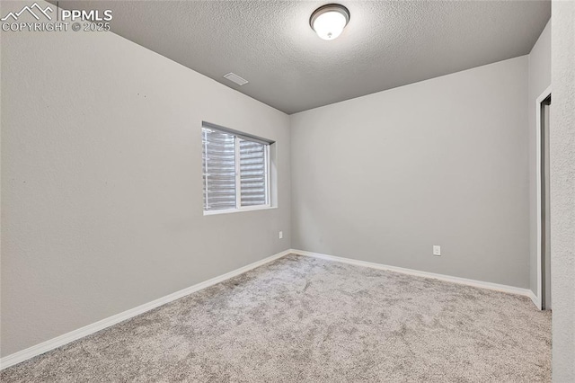 unfurnished room with baseboards, a textured ceiling, visible vents, and carpet