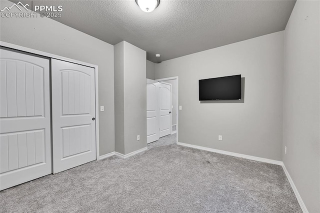 unfurnished bedroom with baseboards, carpet flooring, a textured ceiling, and a closet