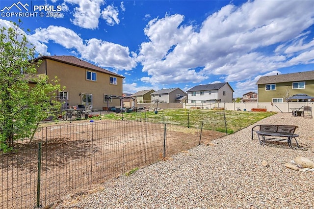 view of yard featuring fence, a fire pit, and a residential view