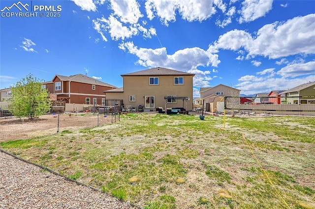 rear view of property featuring fence, a residential view, and stucco siding