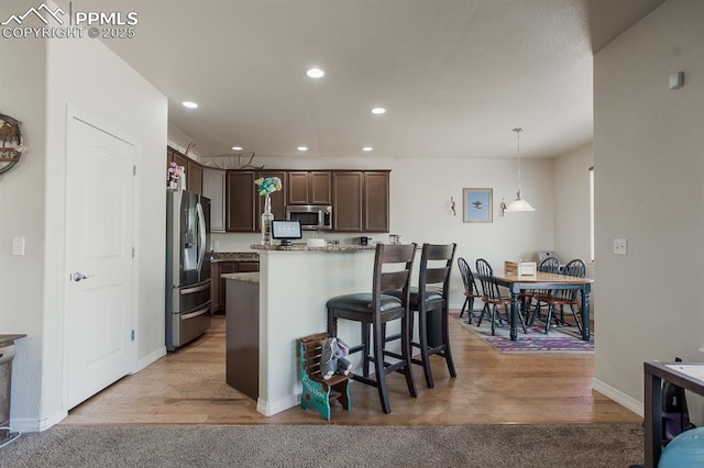 6117 Hayfield Pl, Colorado Springs, CO 80925 - kitchen with pendant lighting, dark brown cabinets, recessed lighting, stainless steel appliances, and a breakfast bar area