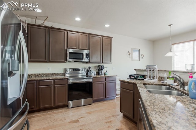 6117 Hayfield Pl, Colorado Springs, CO 80925 - kitchen with dark brown cabinetry, recessed lighting, appliances with stainless steel finishes, light wood finished floors, and a sink