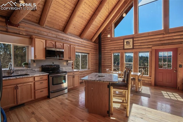876 Obsidian Dr, Florissant, CO 80816 - kitchen with log walls, light stone countertops, beamed ceiling, a sink, and stainless steel appliances