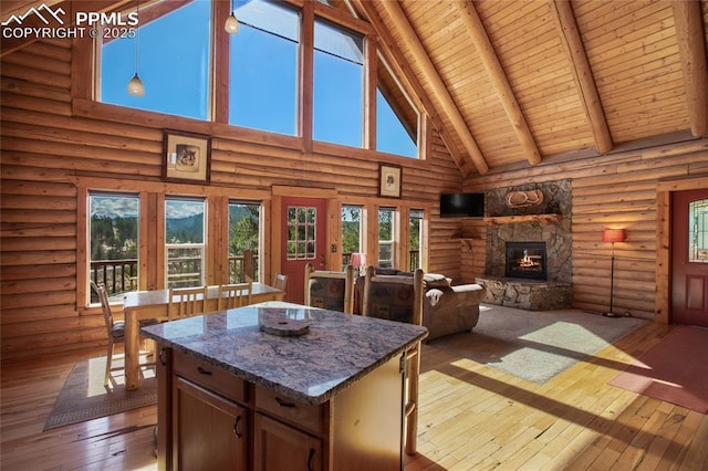 876 Obsidian Dr, Florissant, CO 80816 - interior space featuring a stone fireplace, hardwood / wood-style flooring, beam ceiling, high vaulted ceiling, and log walls