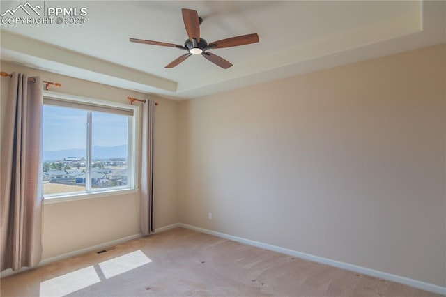 1474 Promontory Bluff Vw, Colorado Springs, CO 80921 - spare room featuring light colored carpet, a ceiling fan, a raised ceiling, and baseboards