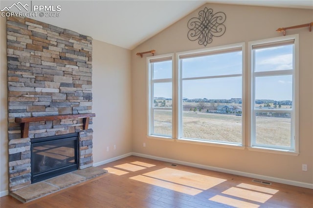 1474 Promontory Bluff Vw, Colorado Springs, CO 80921 - unfurnished living room featuring wood finished floors, lofted ceiling, healthy amount of natural light, a fireplace, and baseboards
