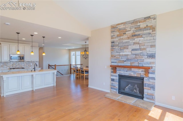 1474 Promontory Bluff Vw, Colorado Springs, CO 80921 - living room featuring light wood finished floors, a chandelier, a fireplace, baseboards, and recessed lighting