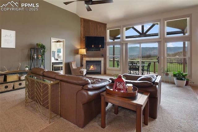 15090 Jessie Dr, Colorado Springs, CO 80921 - carpeted living room featuring a ceiling fan, a tiled fireplace, plenty of natural light, and high vaulted ceiling
