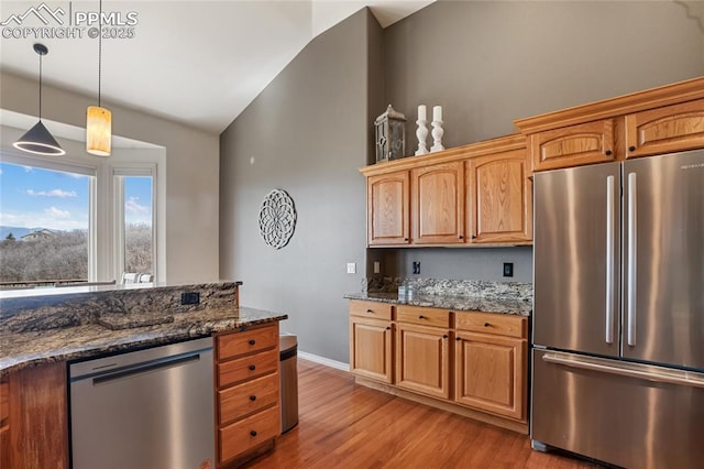 15090 Jessie Dr, Colorado Springs, CO 80921 - kitchen with appliances with stainless steel finishes, vaulted ceiling, light wood finished floors, dark stone counters, and decorative light fixtures
