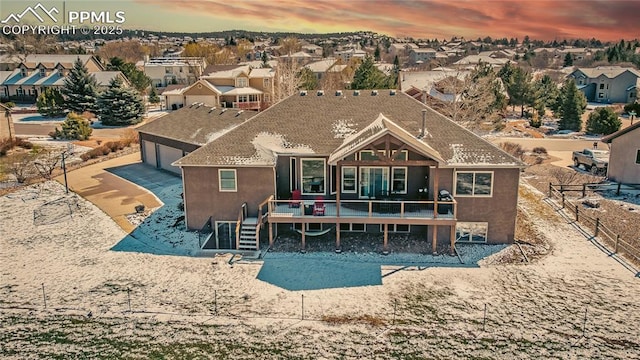 15090 Jessie Dr, Colorado Springs, CO 80921 - back of property at dusk featuring a wooden deck, driveway, a residential view, stucco siding, and a garage