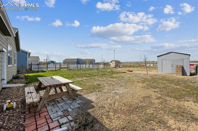view of yard featuring fence, an outdoor structure, and a storage shed