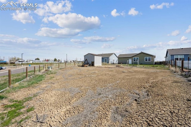 view of yard featuring fence, a rural view, and an outdoor structure