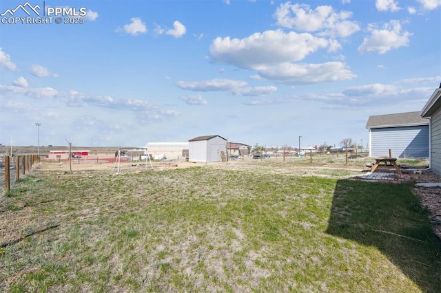 view of yard with an outdoor structure, fence, and a storage shed