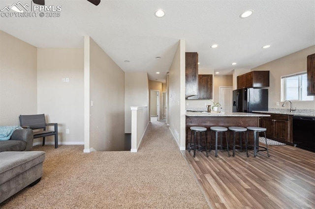 kitchen with a kitchen breakfast bar, dark brown cabinets, black appliances, open floor plan, and a peninsula