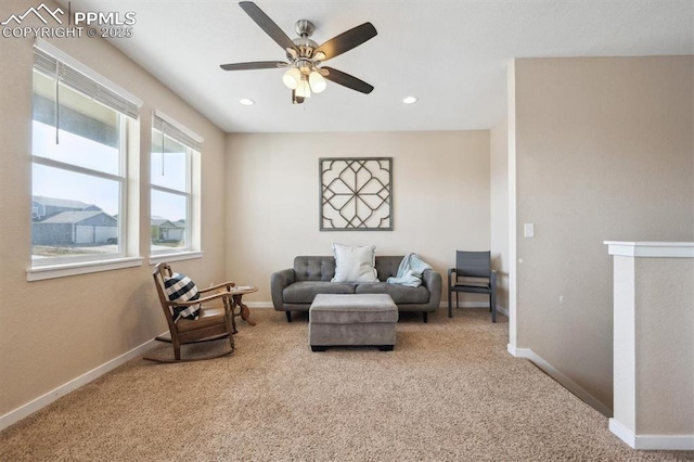 living area featuring ceiling fan, baseboards, and carpet