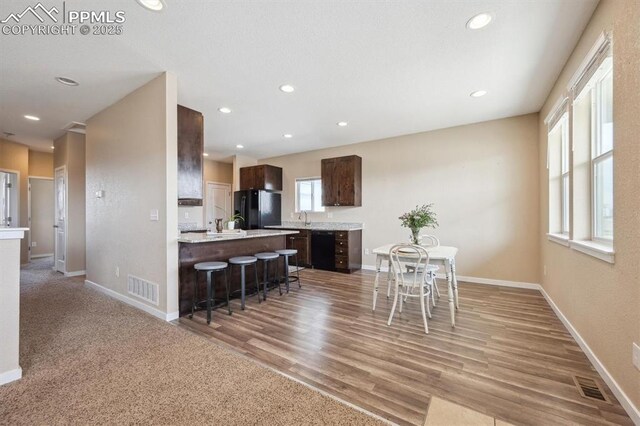 kitchen with black appliances, dark brown cabinetry, visible vents, and light countertops