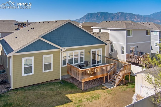 1185 Antrim Loop, Colorado Springs, CO 80910 - rear view of property featuring fence, a deck with mountain view, a shingled roof, and a lawn