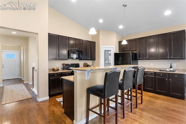 1185 Antrim Loop, Colorado Springs, CO 80910 - kitchen featuring pendant lighting, light wood-style flooring, black appliances, a breakfast bar, and a center island
