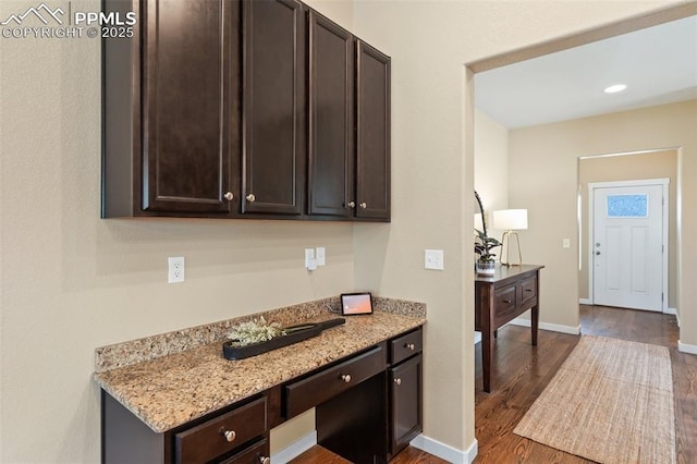 1185 Antrim Loop, Colorado Springs, CO 80910 - kitchen featuring baseboards, dark wood finished floors, dark brown cabinets, light stone countertops, and built in study area