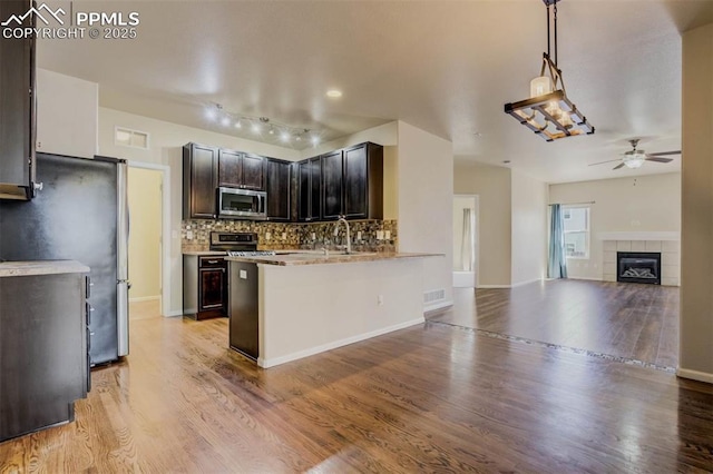 7935 Morning Dew Rd, Colorado Springs, CO 80908 - kitchen with tasteful backsplash, open floor plan, light wood-style flooring, ceiling fan, and appliances with stainless steel finishes