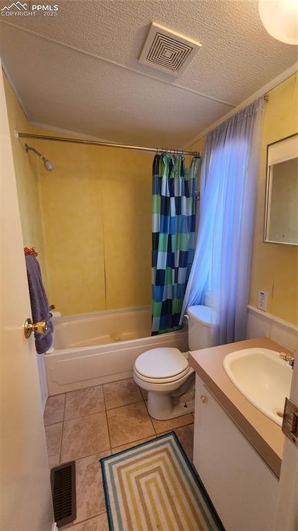 bathroom with shower / tub combo, toilet, a textured ceiling, tile patterned floors, and vanity