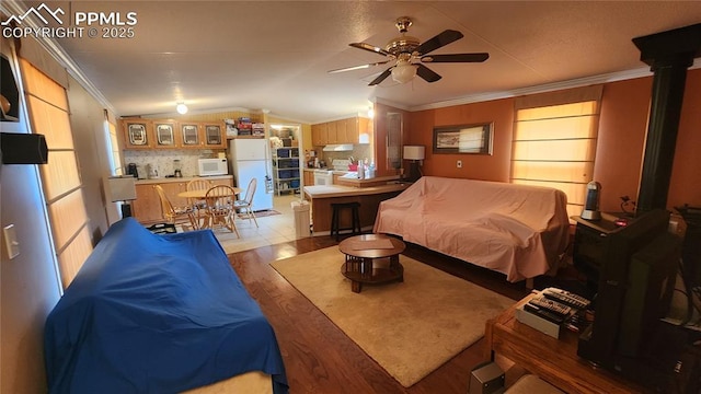 bedroom with freestanding refrigerator, lofted ceiling, wood finished floors, and ornamental molding