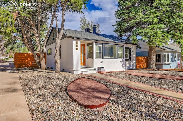 bungalow featuring stucco siding and fence