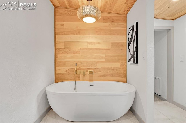 bathroom featuring wood ceiling, baseboards, wood walls, and a freestanding tub